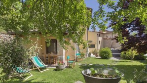 A well-maintained garden with a lawn, a stone pathway, a green chair, and a table with chairs under a tree. - Il Girasole by Interhome (Camaiore)