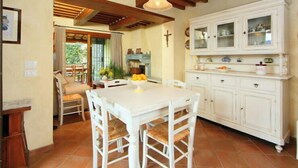 A dining area with a white table and chairs, a kitchen with white cabinets, and a wooden ceiling. - Il Girasole by Interhome (Camaiore)