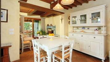 Un coin repas avec une table et des chaises blanches, une cuisine avec des meubles blancs et un plafond en bois.