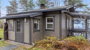 Une petite cabane avec une véranda, une cheminée et une statue d’ours.