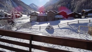 A snow-covered village with wooden houses and a clear view of mountains.