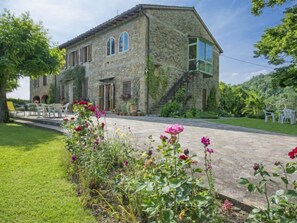 Un bâtiment en pierre doté d’un jardin et d’un espace extérieur aménagé pour s’asseoir.