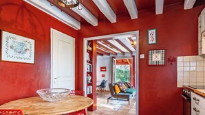 Una cocina con una mesa y sillas de madera, una pared roja y vista al área de estar.