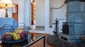 A room with a stone fireplace, a lamp, and a basket of fruit on a table. - Le Dahu by Interhome (Nendaz)