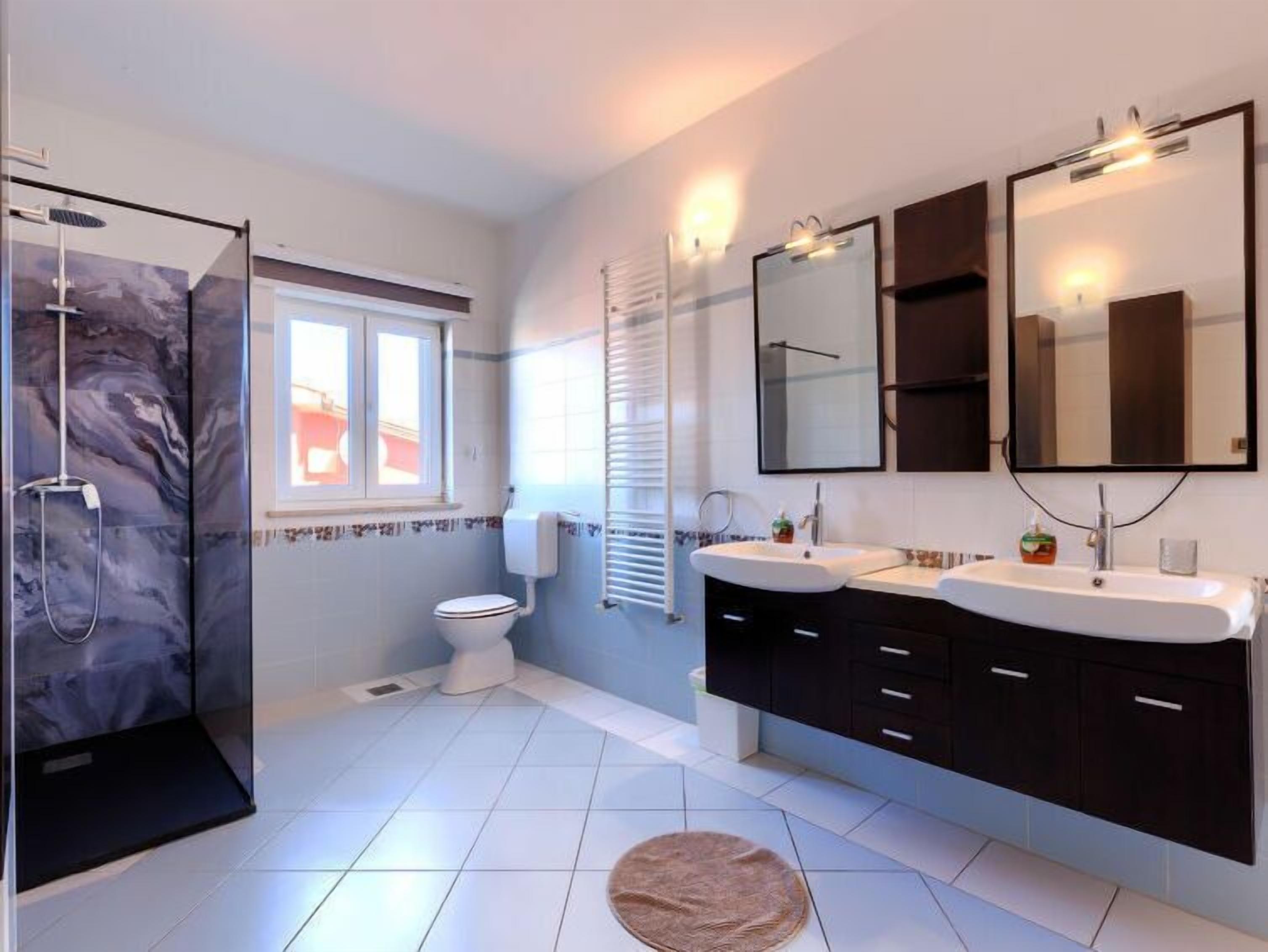 Une salle de bain moderne avec deux lavabos, une douche et des toilettes.