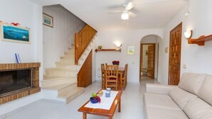 Ein Wohnzimmer mit Kamin, einer Holztreppe, einem Esstisch und einer Couch.
