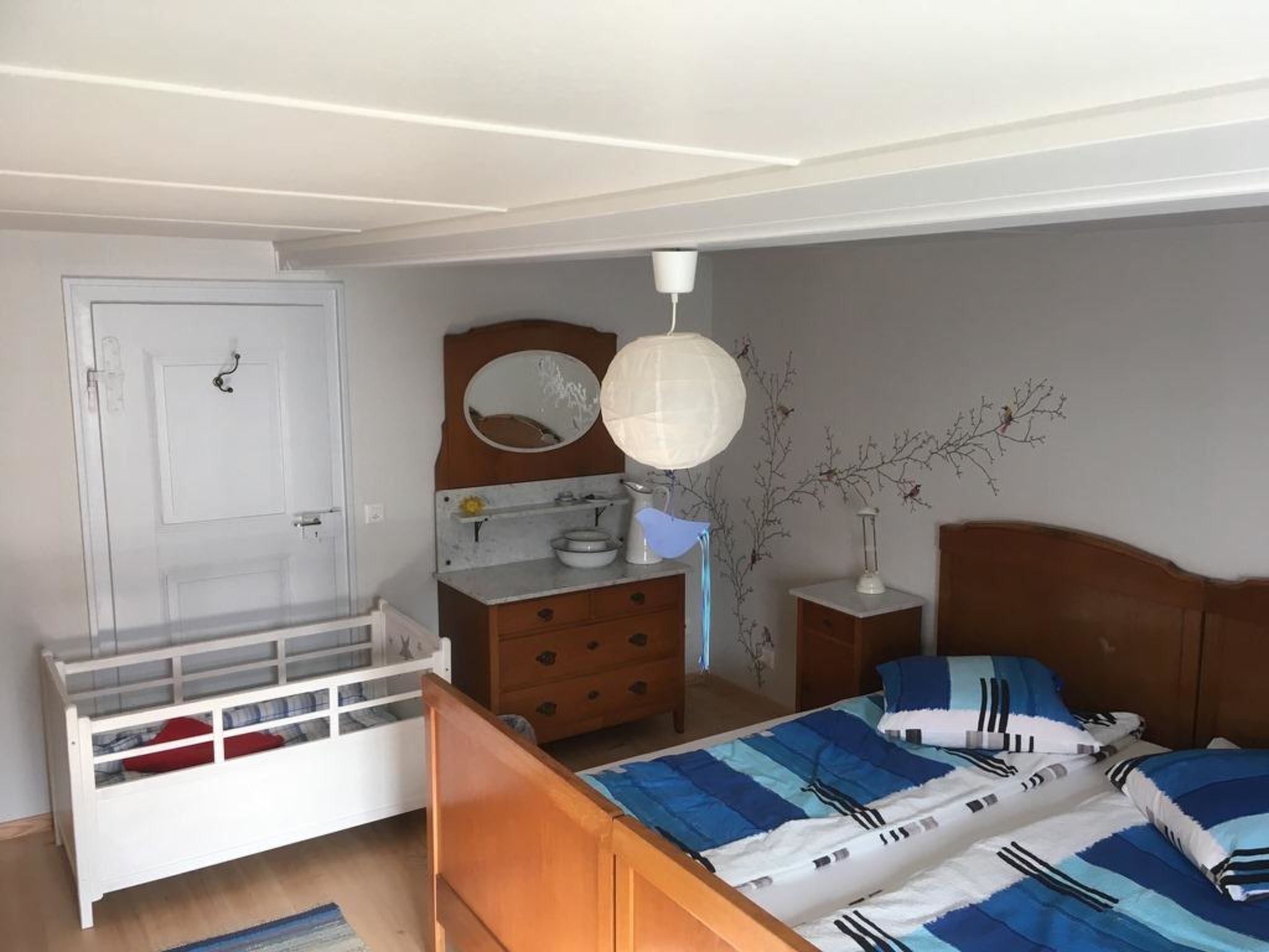 Un dormitorio con una cama, cómoda y una mesita de noche con lámpara.