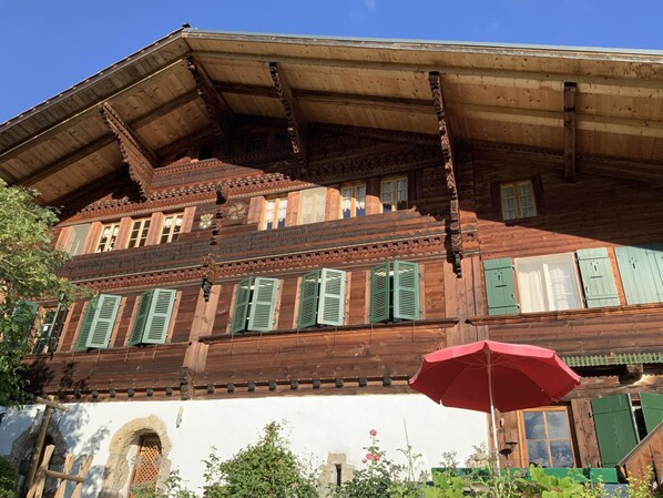 A traditional wooden building with a sloped roof and green shutters.