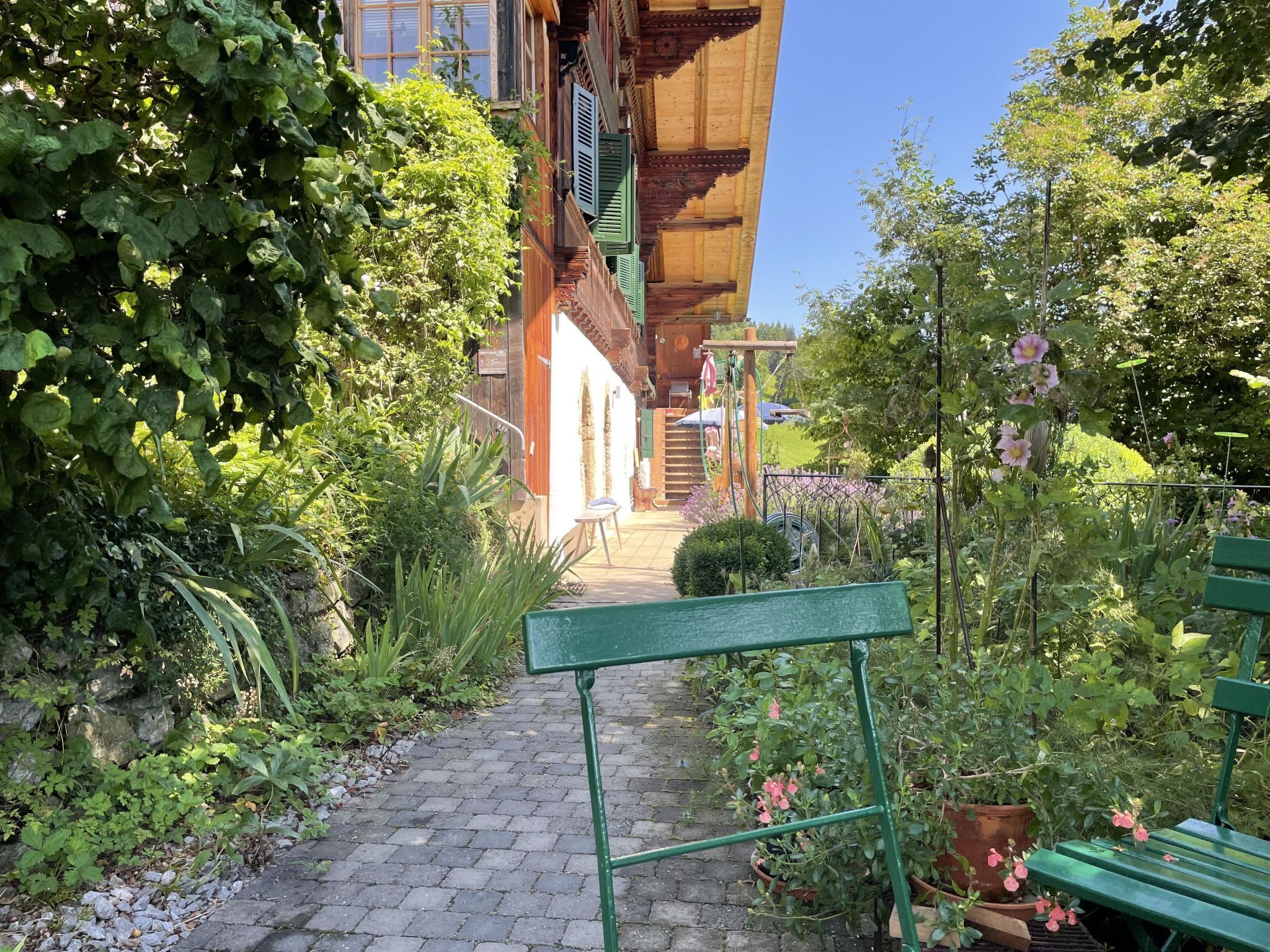 A garden pathway leading to a wooden building with a staircase.