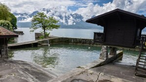 A stone dock extending into a calm lake with a mountain backdrop. - Duck House by Interhome (Montreux)