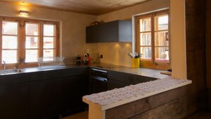 Eine Küche mit Holzbalken, einem Spülbecken, einem Wäscheständer und einem Fenster mit Außenblick.
