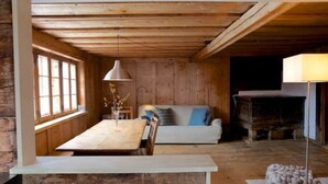 Ein rustikales Holzinterieur mit Esstisch, Sofa und Lampe.