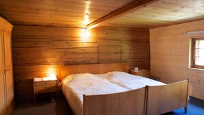 Ein Schlafzimmer einer Holzhütte mit einem Bett, Nachttischen und einem Fenster.