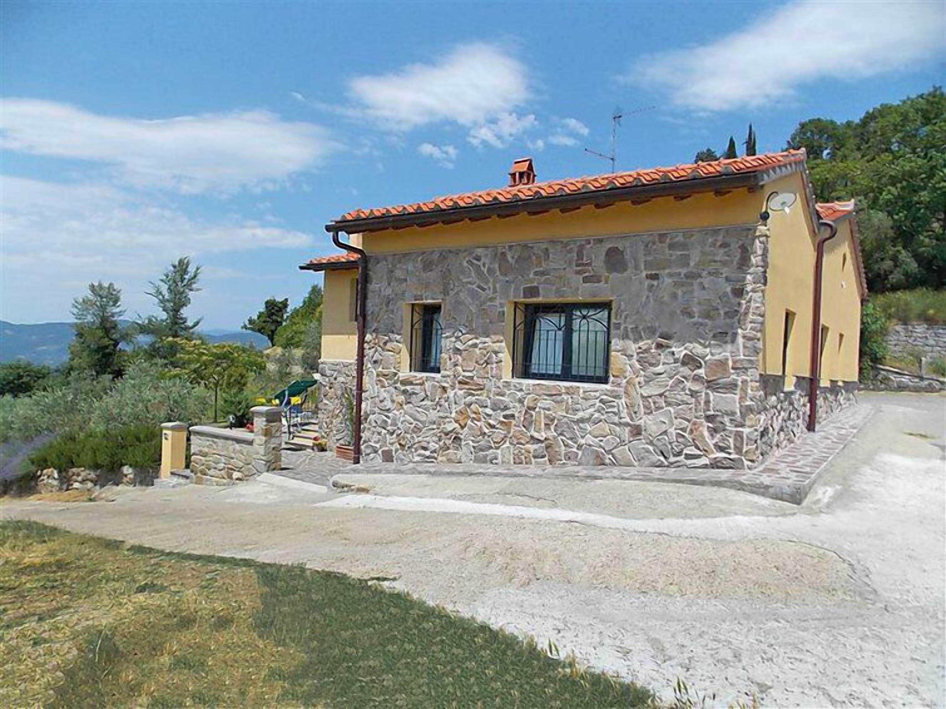 Une maison en pierre avec un toit recouvert de tuiles rouges, une petite fenêtre et un mur en pierre.