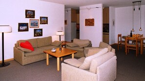 A living room with a sofa, armchairs, a coffee table, and a dining table with chairs. There are framed pictures on the walls and a lamp on the floor. - Disentiserhof Aua Cotschna Avvanzino by Interhome (Disentis)
