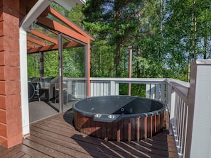 A wooden deck with a hot tub, outdoor furniture, and a pergola. - Kannelpirtti 2 by Interhome (Liperi)