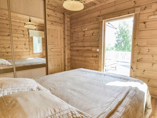 Un dormitorio de cabaña de madera con cama, espejo y ventana.
