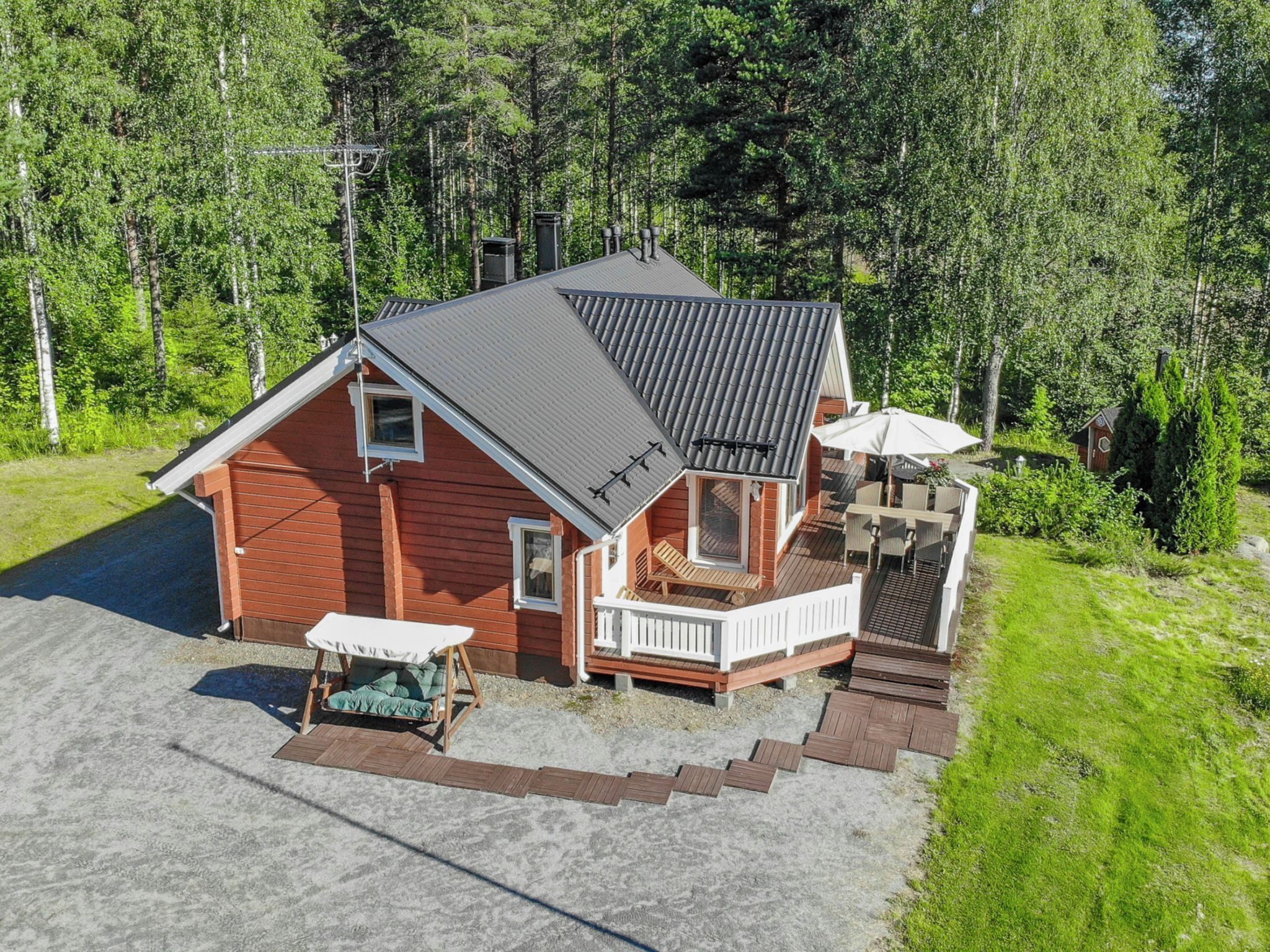 A two-story cabin with a porch, a deck, and a small outdoor seating area.