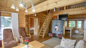 A cozy log cabin interior with a fireplace, wooden furniture, and a staircase. - Kannelpirtti 2 by Interhome (Liperi)