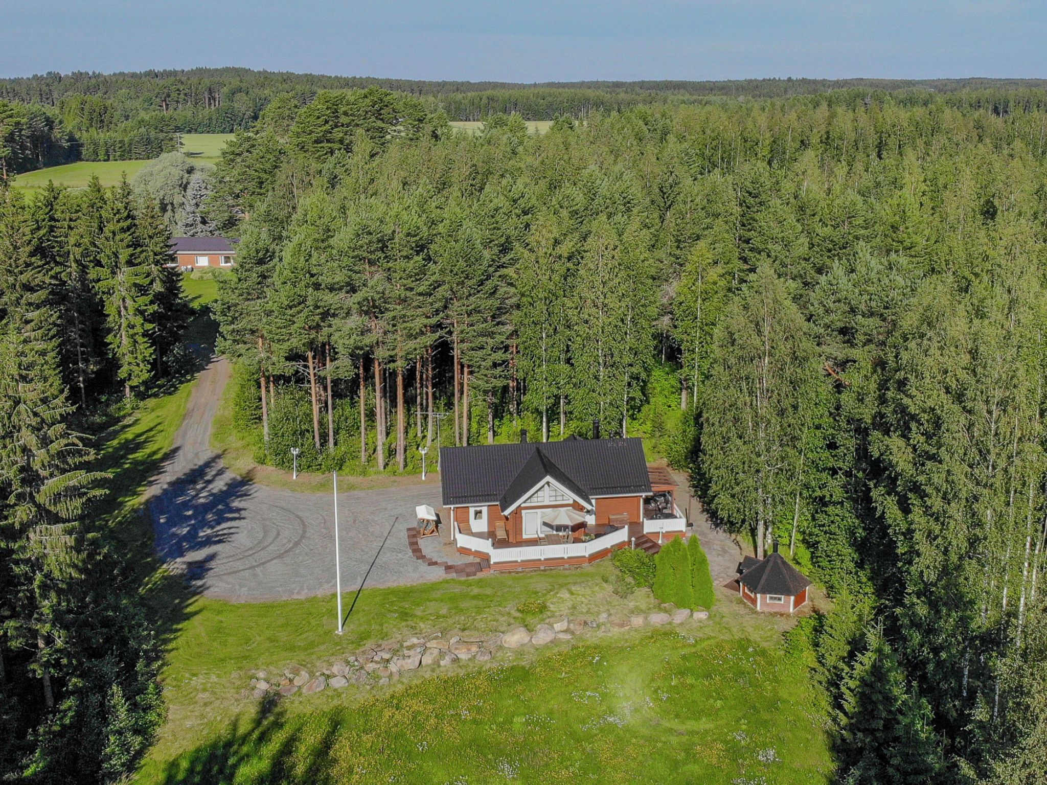 Une maison entourée d’une forêt dense, avec une allée pavée menant à l’entrée.