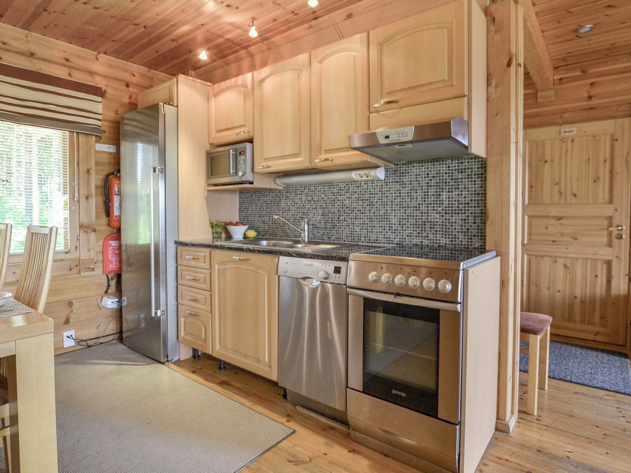 Una cocina moderna con electrodomésticos de acero inoxidable, armarios de madera y un salpicadero de azulejos.