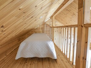 A wooden interior with a bed in the center.