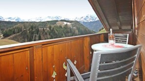 A wooden balcony with a table and chairs, overlooking a mountainous landscape with snow-capped peaks. - Schmittnhof by Interhome (Umhausen)