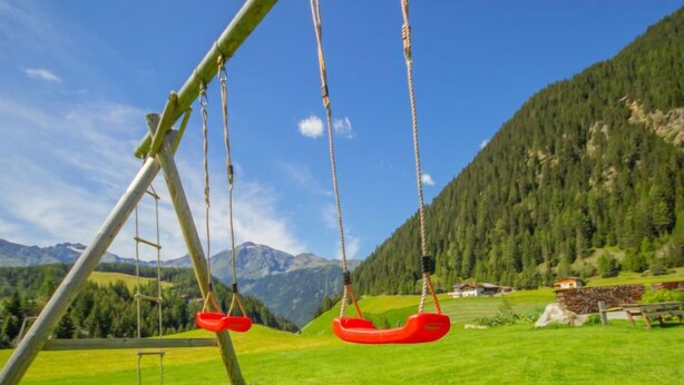 A swing set in a grassy field with a mountain backdrop. - Schmittnhof by Interhome (Umhausen)