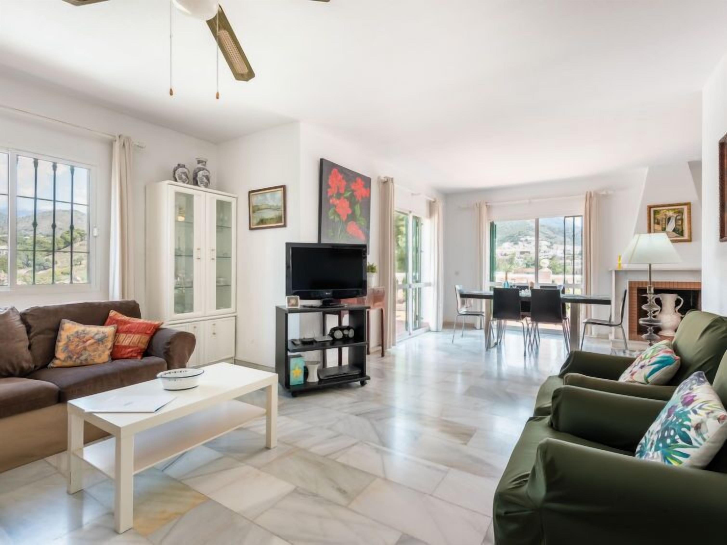 A spacious living room with a sofa, coffee table, TV, and dining area.