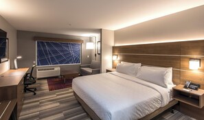 A hotel room with a large bed, a desk, a chair, a desk lamp, a wall-mounted lamp, an air conditioning unit, and a large window with a geometric pattern. - Holiday Inn Express & Suites Phoenix North - Happy Valley by IHG (Phoenix)
