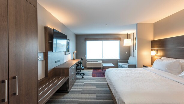 A hotel room with a large bed, a desk with a chair, a TV mounted on the wall, and a window providing natural light. - Holiday Inn Express & Suites Phoenix North - Happy Valley by IHG (Phoenix)