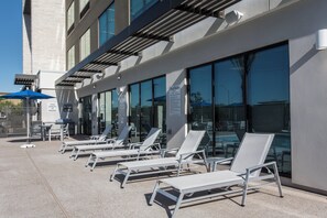 A poolside area with lounge chairs and umbrellas, a sign indicating shallow water, and a lifeguard warning. - Holiday Inn Express & Suites Phoenix North - Happy Valley by IHG (Phoenix)
