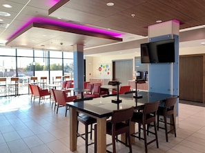 A modern cafe with a bar area, red chairs, and a large window. - Holiday Inn Express & Suites Phoenix North - Happy Valley by IHG (Phoenix)