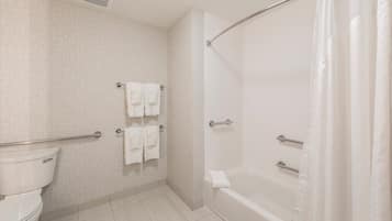 A bathroom with a toilet, a shower with a glass door, and two towel racks with towels.