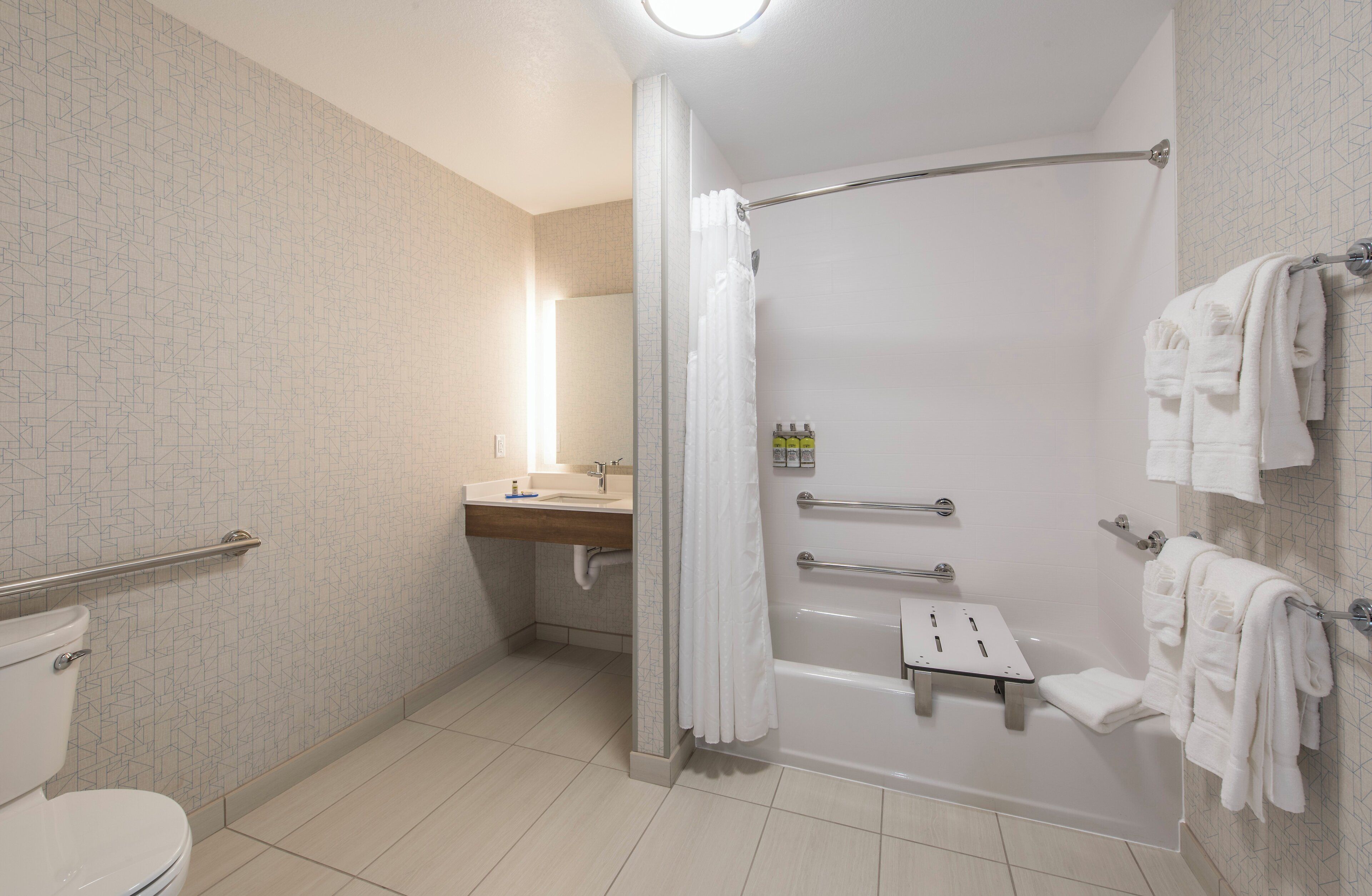 Une salle de bain moderne avec une douche à l’italienne, des toilettes, un lavabo et un porte-serviettes.