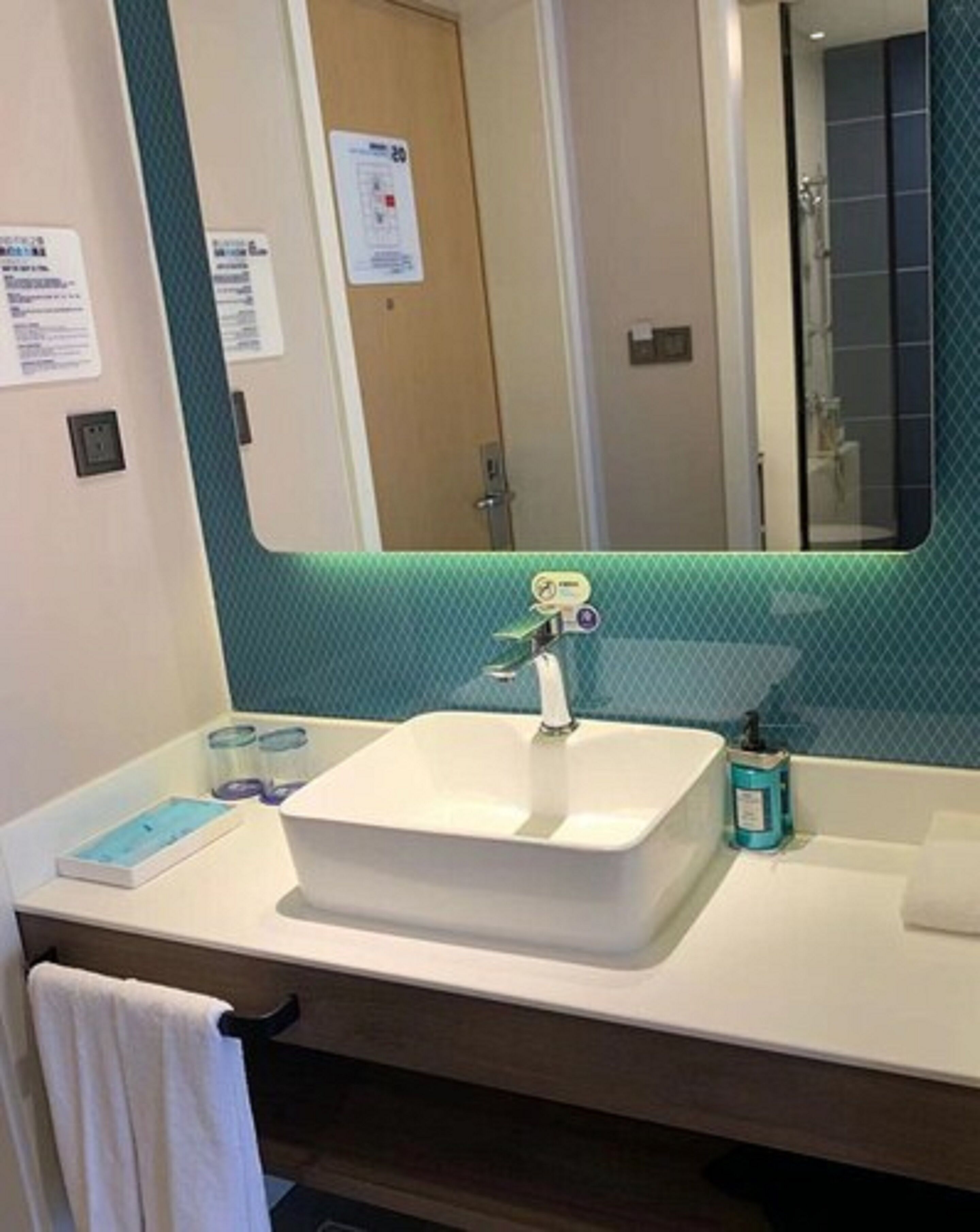 A bathroom with a white sink, a mirror, and a towel rack.