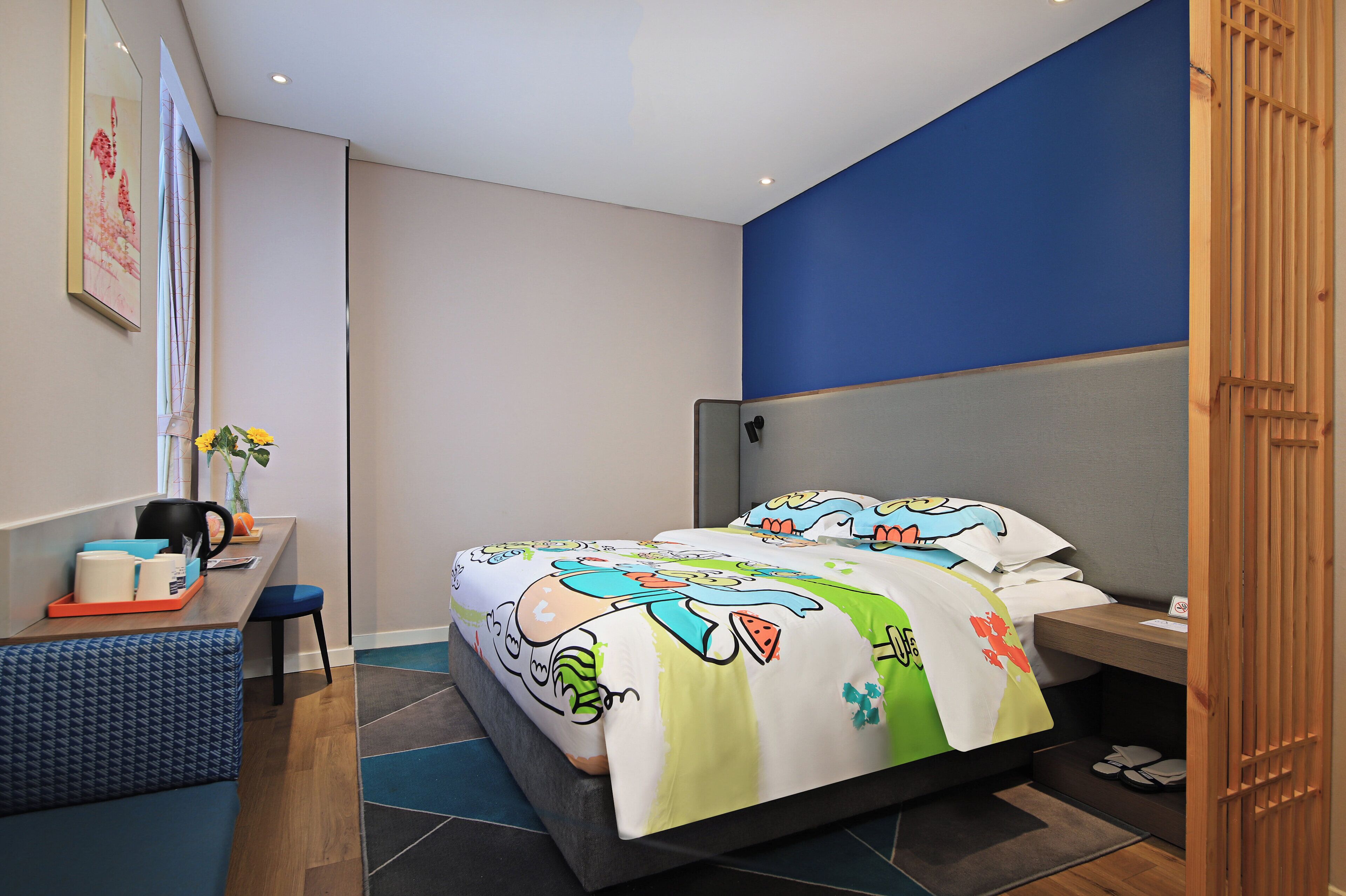 A modern hotel room with a bed, a desk, and a chair.