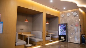 A modern interior with seating areas, a vending machine, clocks, and a no-smoking sign. - Holiday Inn Express Linyi West by IHG (Linyi)