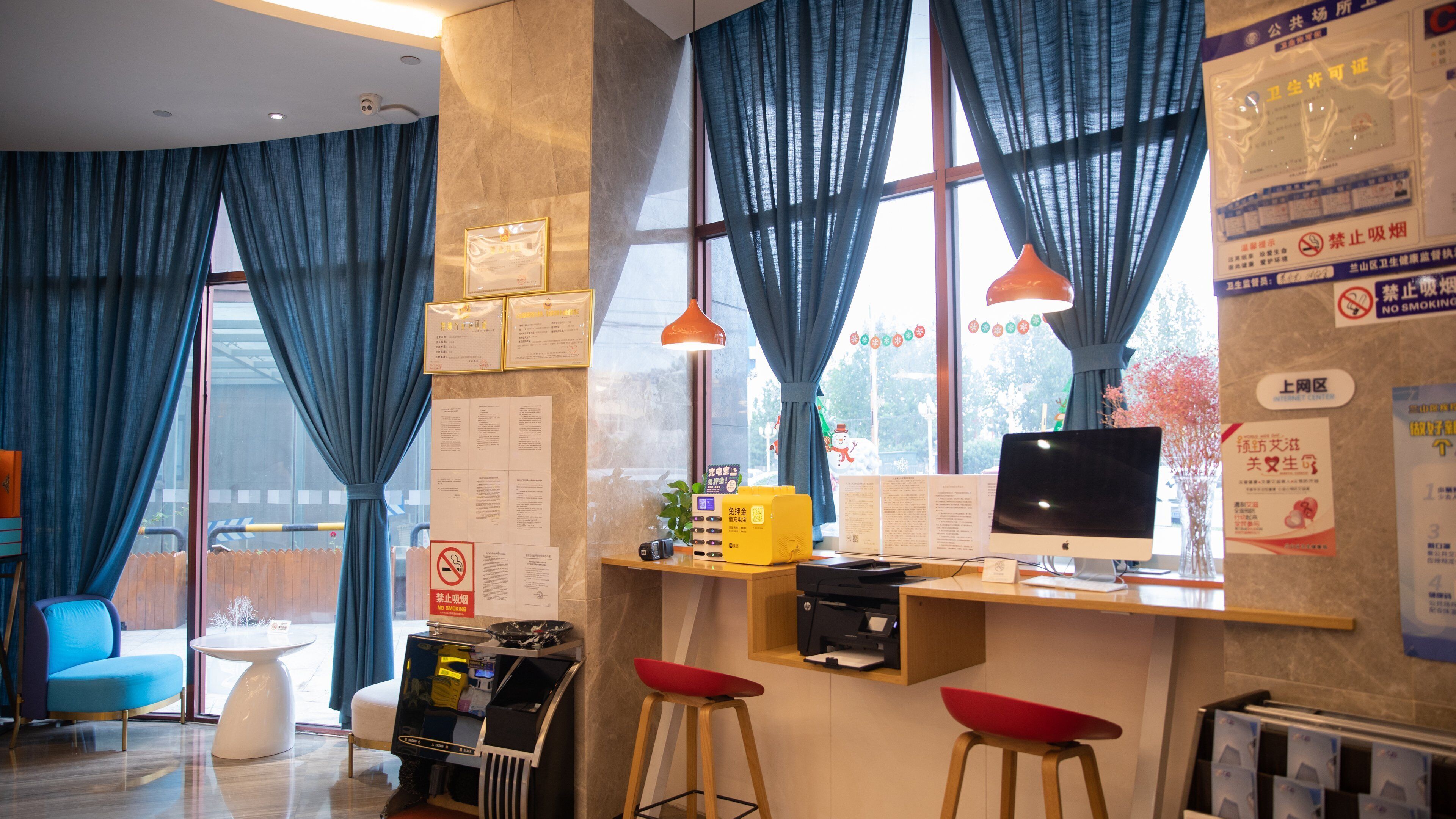 A modern office space with a desk, computer, and two red stools.