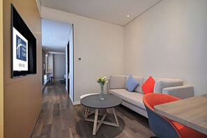 A modern hotel room with a sofa, a round table, and a vase of flowers. - Holiday Inn Express Linyi West by IHG (Linyi)