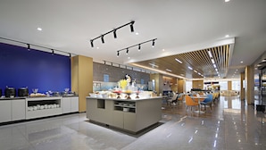 A modern hotel lobby with a central island, seating area, and a blue accent wall.