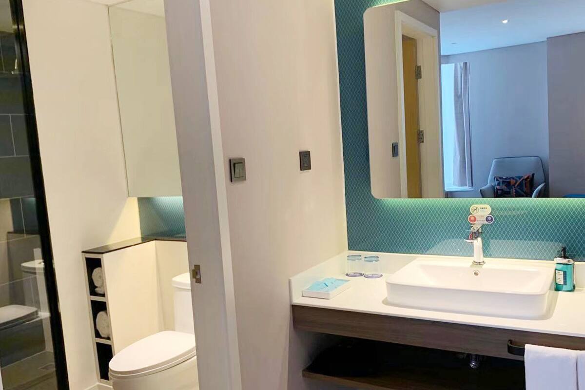 A modern bathroom with a white sink, mirror, and a toilet.