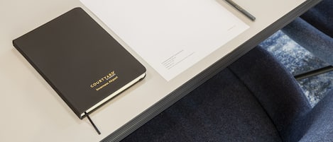 Un cuaderno con la etiqueta "COURTYARD" y una hoja en blanco sobre una mesa.