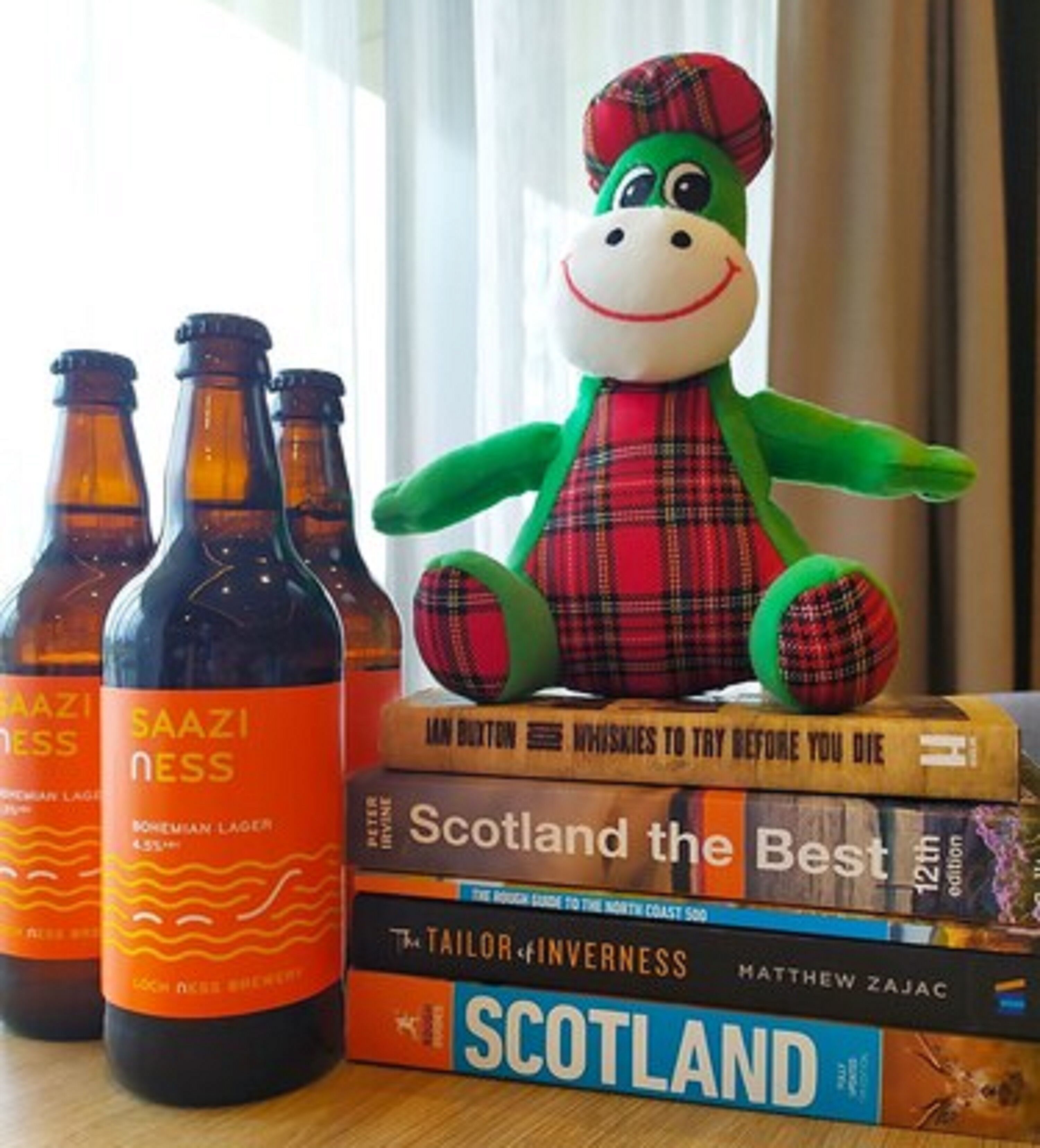 Een verzameling bierflesjes, een pluchen knuffel en een stapel boeken op een tafel.