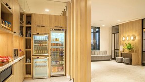 A modern kitchen with wooden cabinets, a built-in refrigerator, and a seating area with a sofa and a plant. - Courtyard by Marriott Inverness Airport (Inverness)