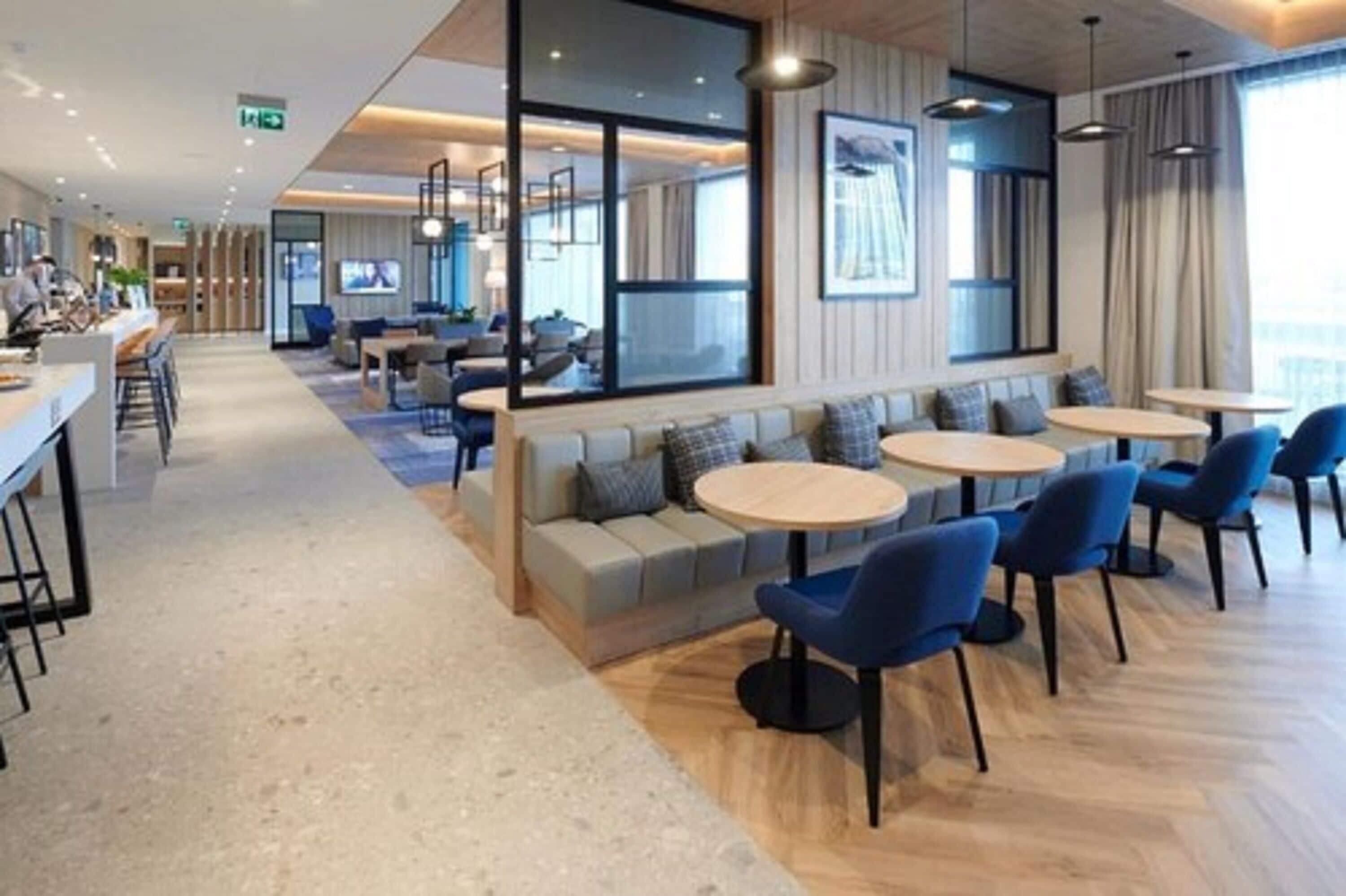 A modern hotel lobby with a seating area, a bar, and a large window.