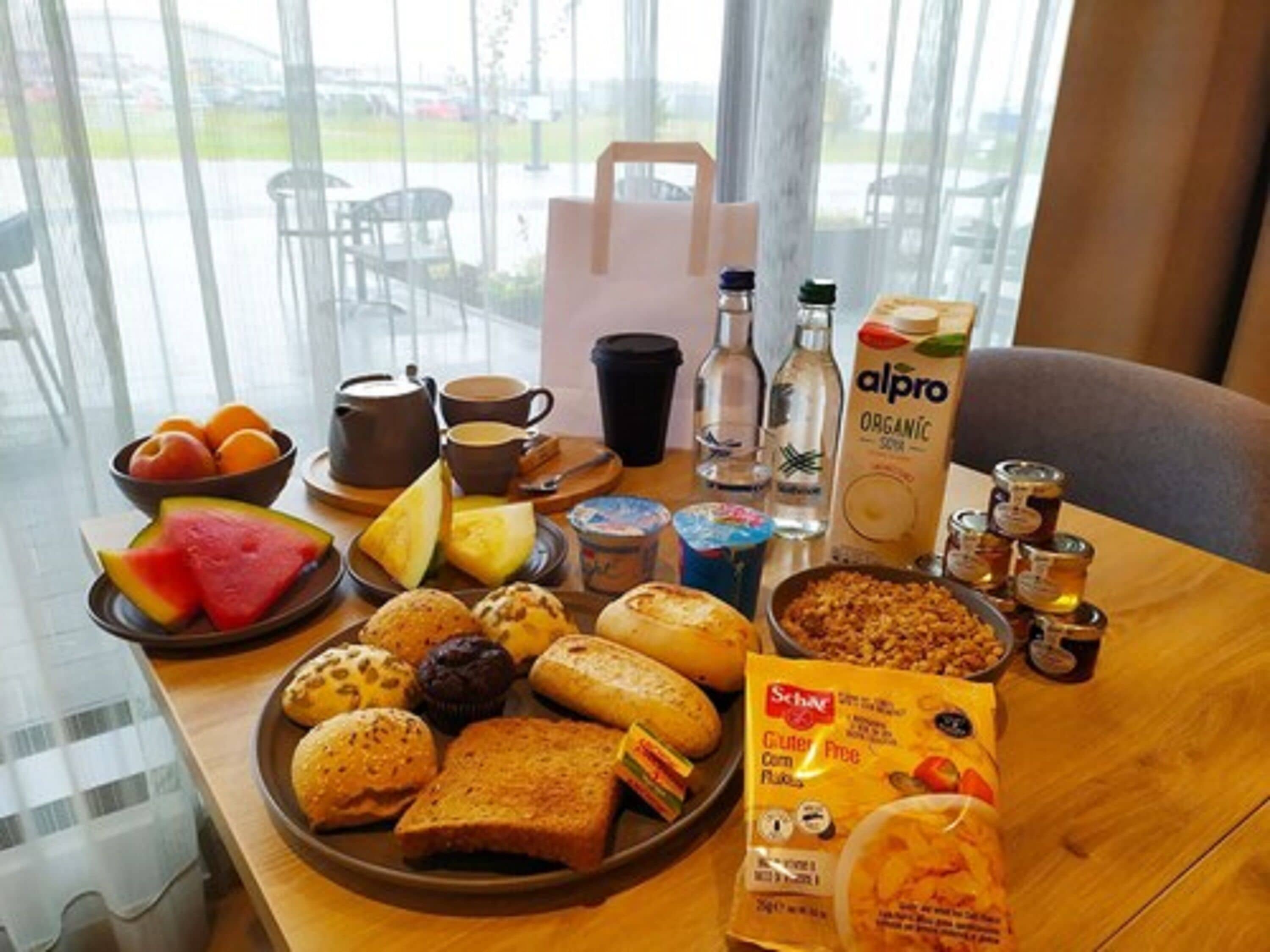A breakfast table with various foods, drinks, and a carton of organic milk.