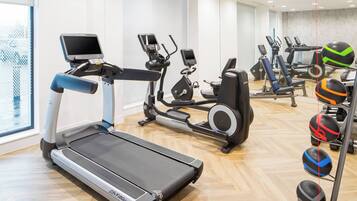 A gym with treadmills, elliptical machines, and a variety of exercise balls.