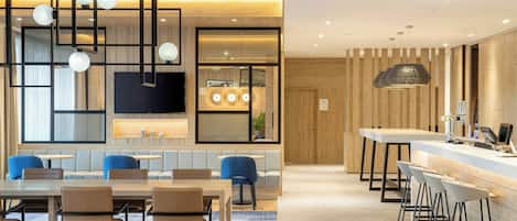 Un vestíbulo de hotel moderno con zona de estar, bar y área de cocina.