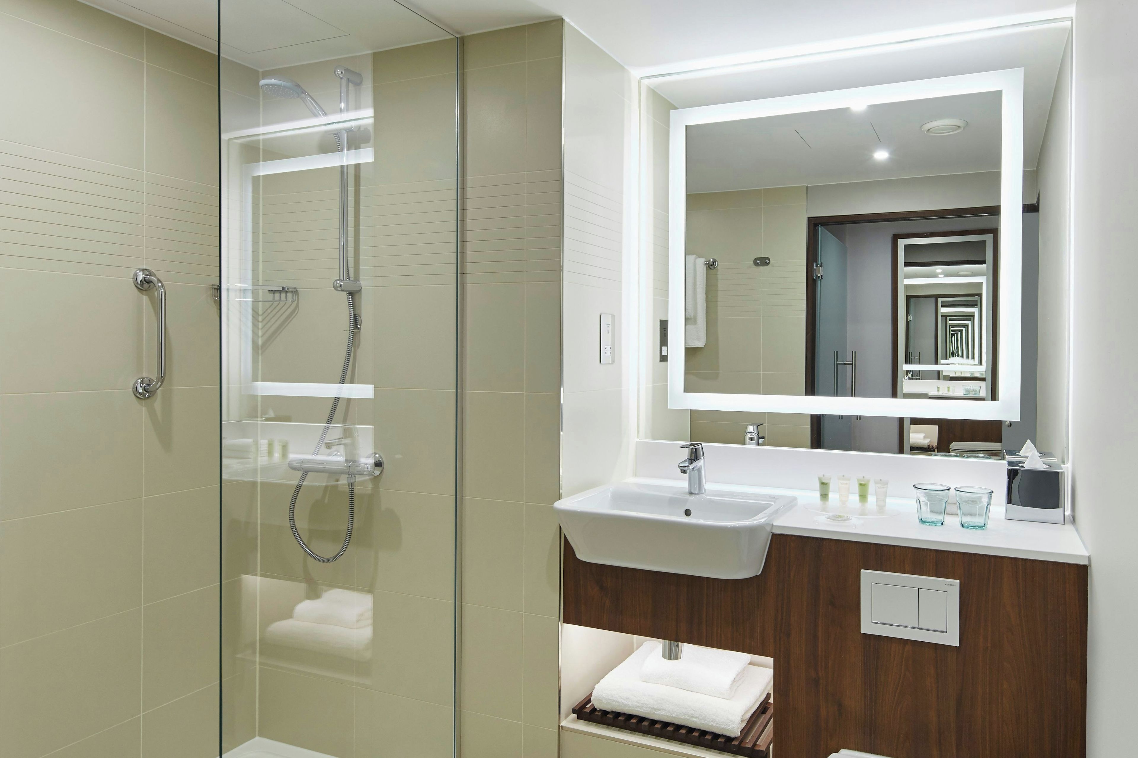A modern bathroom with a glass-enclosed shower, a vanity with a sink, and a large mirror.